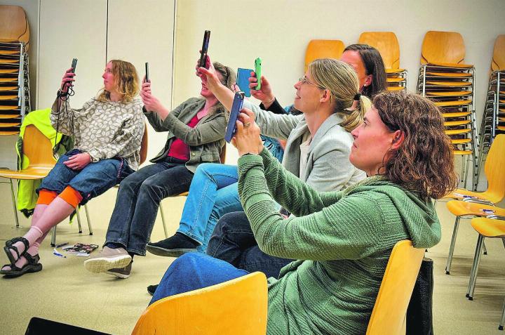Konzertiert scannen die Teilnehmerinnen einen QR-Code für weiterführende Informationen ein.