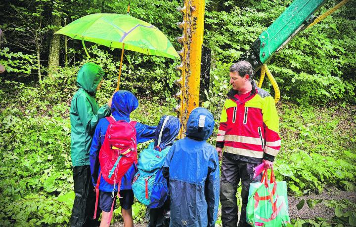 Roman Brazerol erklärt die Funktionsweise der riesigen Heckenschere, die vom Forstwart für die Waldpflege eingesetzt wird. Bild: Marianne Burgener