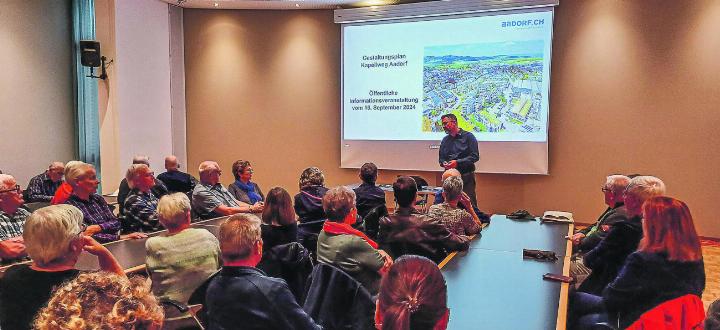 Gemeindepräsident Matthias Küng informiert fast hundert Interessierte über die geplante Grossüberbauung in Zentrumsnähe von Aadorf. Bild: Kurt Lichtensteiger