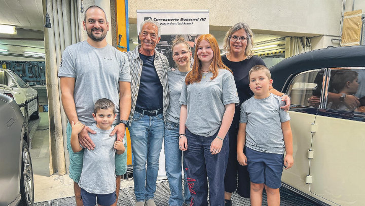 Othmar (l.) und Monika Thöni (r.) mit Nachwuchs und Team am Samstag in der Werkstatt zwischen Oldtimer und Elektrofahrzeugmit Hagelschaden. 2. von links: der ehemalige Inhaber Manfred Bossard. Bild: Bettina Sticher